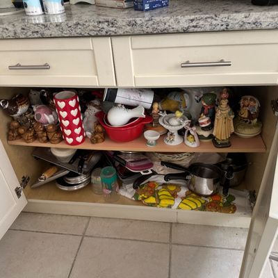 Sale Photo Thumbnail #41: Open kitchen cabinet filled with various collectibles, figurines, red Pyrex mixing bowls, heart-patterned vase, and cookware items.