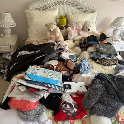 Sale Photo Thumbnail #52: Assorted clothing, plush toys, and accessories piled on a bed with a white wicker headboard and matching nightstands.