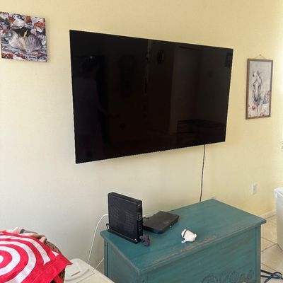 Sale Photo Thumbnail #34: Wall-mounted flat-screen television situated above a teal painted wooden trunk with carved details.