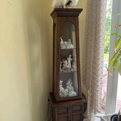 Sale Photo Thumbnail #9: Tall vintage dark wood curio cabinet featuring arched glass panel doors and lower storage, filled with collectible figurines.