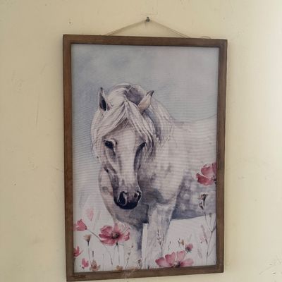Sale Photo Thumbnail #33: Framed watercolor print of a white horse standing among pink flowers, enclosed in a simple rustic wooden frame with a hanging cord.