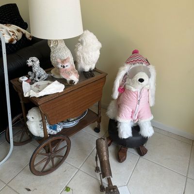 Sale Photo Thumbnail #6: Vintage wooden drop-leaf tea cart featuring large spoked wheels, displaying a textured owl table lamp, bird figurines, and surrounding decor items.