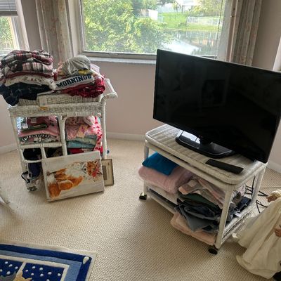 Sale Photo Thumbnail #48: Two white wicker rolling carts holding folded clothing and linens, paired with a flat-screen LG television and small decorative fox canvas artwork.