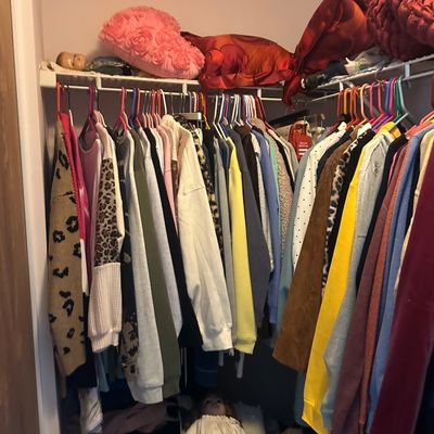 Sale Photo Thumbnail #61: Walk-in closet filled with hanging women's clothing, including sweaters and jackets, alongside decorative throw pillows on the upper shelf.