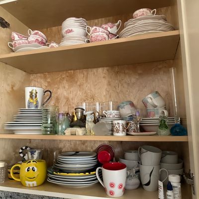 Sale Photo Thumbnail #36: Kitchen cabinet filled with a variety of dishware, novelty mugs, glassware, and red Transferware fine china.