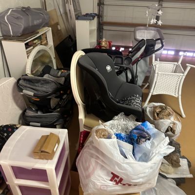 Sale Photo Thumbnail #27: Collection of baby gear and household items including a convertible car seat, stroller, bassinet, and plastic storage drawers in a garage.