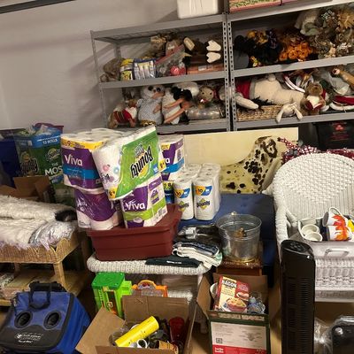 Sale Photo Thumbnail #26: Garage storage scene with white wicker furniture, bulk paper towels, seasonal decorations, household goods, and metal shelving units.