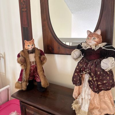 Sale Photo Thumbnail #63: Pair of vintage anthropomorphic cat dolls dressed in ornate renaissance-style royalty attire, displayed atop a wooden cabinet.