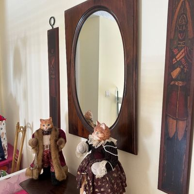 Sale Photo Thumbnail #64: Pair of vintage dressed anthropomorphic cat figures standing in front of a dark wood oval wall mirror and flanking soldier wall art panels.