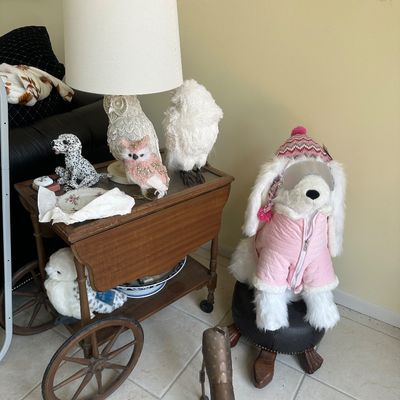 Sale Photo Thumbnail #7: Vintage drop-leaf tea cart with large wooden wheels, displayed with an owl-form table lamp, owl figurines, and a large stuffed dog in winter attire perched on a footstool.