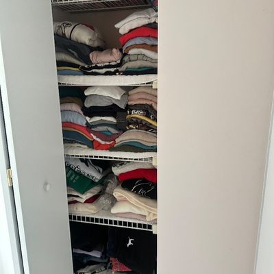 Sale Photo Thumbnail #54: Closet filled with neatly stacked casual women's clothing, including sweaters, t-shirts, and pants on wire shelving.