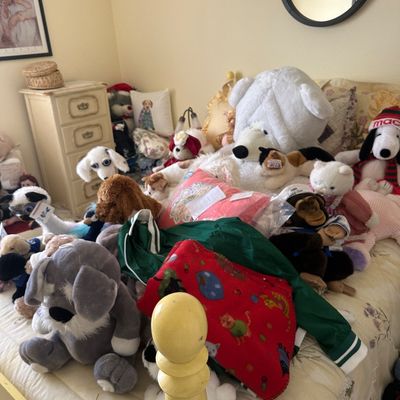 Sale Photo Thumbnail #85: Large collection of plush stuffed animals, including dogs, bears, and a monkey, displayed on a bed.