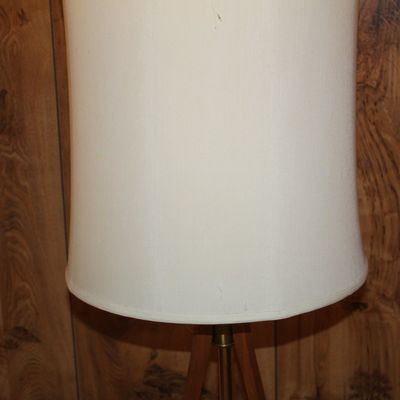 Sale Photo Thumbnail #95: Vintage mid-century floor lamp with a tall off-white drum shade and a wooden tripod-style base.