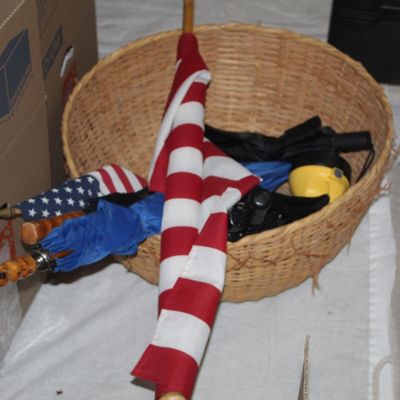 Sale Photo Thumbnail #148: Large shallow woven basket containing small American flags, umbrellas, and various hand tools or accessories.