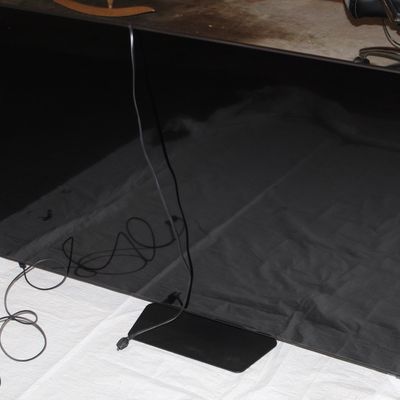 Sale Photo Thumbnail #137: Large flat-screen smart television on a black metal base stand, complete with attached power cord.