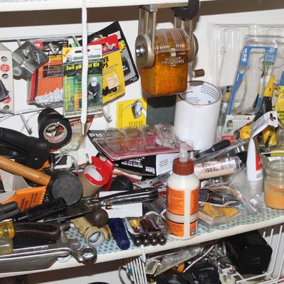 Sale Photo Thumbnail #133: An assortment of household tools and supplies inside a wooden cabinet, including hand tools, glue, batteries, and hardware accessories.