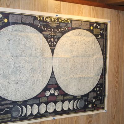 Sale Photo Thumbnail #87: Vintage National Geographic "The Earth's Moon" wall map poster pinned to a wood-paneled wall, featuring detailed hemisphere maps and astronomical diagrams.