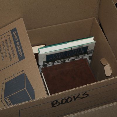 Sale Photo Thumbnail #156: Cardboard moving box labeled "BOOKS" containing various hardcover books, including a copy of *The Irish Americans*.