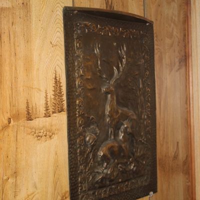 Sale Photo Thumbnail #112: Vintage embossed copper wall plaque featuring a stag and doe in a forest scene, mounted on wood paneling.