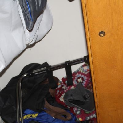 Sale Photo Thumbnail #8: Selection of closet items including hanging garment bags, a folding luggage rack, and a colorful crocheted blanket stored inside a wooden wardrobe.