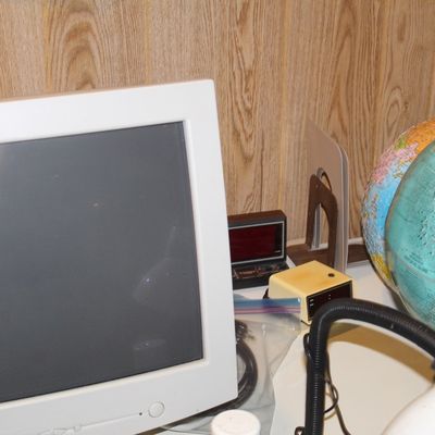 Sale Photo Thumbnail #88: Vintage computer CRT monitor displayed on a desk alongside two world globes, a digital alarm clock, and office accessories.