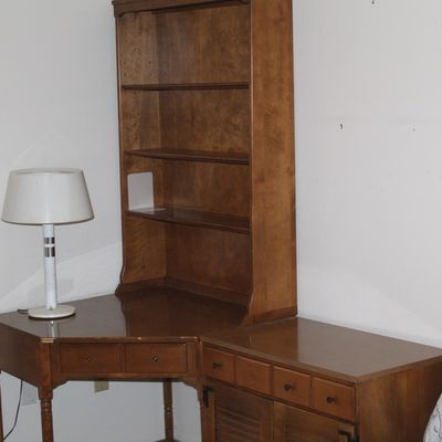 Sale Photo Thumbnail #13: Vintage wooden corner desk with a attached shelving hutch and side storage cabinet, shown alongside a white mid-century style table lamp.