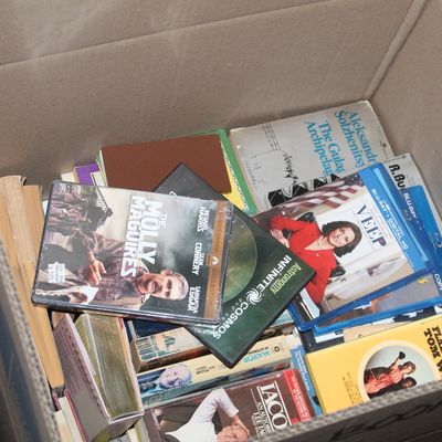 Sale Photo Thumbnail #153: Cardboard box filled with assorted vintage books, DVDs, and Blu-rays, including titles like The Gulag Archipelago and Veep.