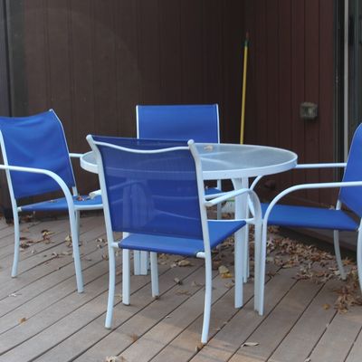 Sale Photo Thumbnail #31: Five-piece outdoor patio set featuring a white metal frame glass-top round table and four matching blue mesh armchairs.