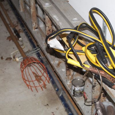 Sale Photo Thumbnail #142: Heavy-duty jumper cables draped over an aluminum extension ladder, alongside a fruit picker tool and household supplies.