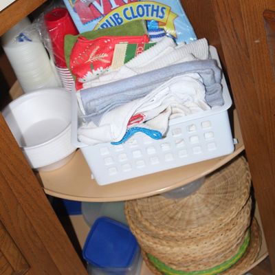 Sale Photo Thumbnail #72: Corner kitchen cabinet with Lazy Susan, organized with cleaning cloths, paper and plastic goods, and woven charger plates.