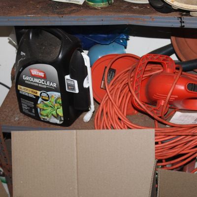 Sale Photo Thumbnail #160: Ortho GroundClear vegetation killer container with comfort wand alongside a coiled red extension cord and lawn tools on a metal shelf.