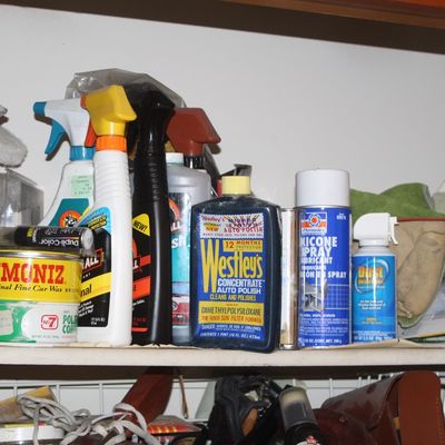 Sale Photo Thumbnail #131: Cabinet shelf filled with vintage automotive care products, including Simoniz car wax tins, Westley's auto polish, and spray lubricants.