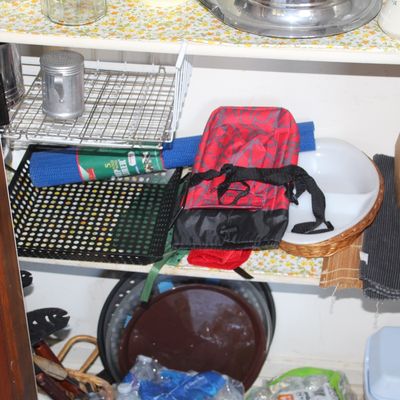 Sale Photo Thumbnail #45: Assorted kitchen goods and storage items in a cabinet, including a wooden knife block, a insulated lunch bag, mesh trays, metal shakers, and serving platters.
