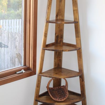 Sale Photo Thumbnail #76: Five-tier wooden corner etagere shelf in a warm honey finish, accompanied by a small woven basket on the bottom shelf.