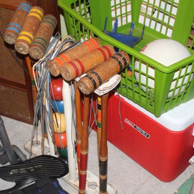 Sale Photo Thumbnail #129: Vintage wooden croquet set with mallets, balls, and metal wickets, shown alongside a red Coleman Polylite cooler and green plastic crate.