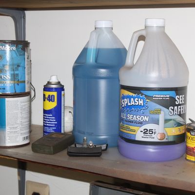 Sale Photo Thumbnail #150: Assorted household chemicals and paint cans arranged on a shelf, including Benjamin Moore house paint, Splash washer fluid, WD-40, and Minwax wood finish.