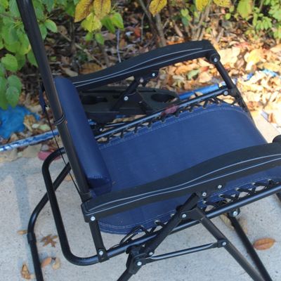 Sale Photo Thumbnail #30: Blue canvas zero gravity reclining patio chair with a black metal frame, armrests, and headrest cushion.