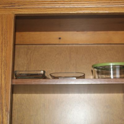Sale Photo Thumbnail #52: Collection of glass and plastic food storage containers displayed inside a wooden cabinet.