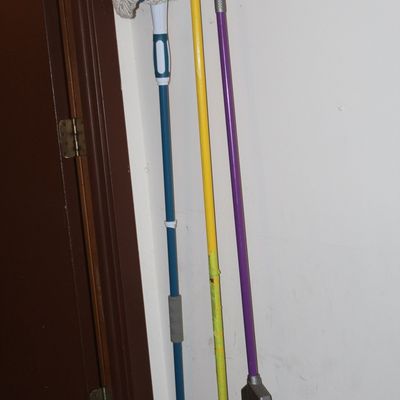 Sale Photo Thumbnail #161: Set of three household cleaning tools including a string mop, a microfiber mop, and a broom, hung from a wall rack.