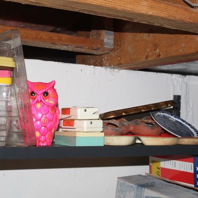 Sale Photo Thumbnail #105: Collection of vintage basement shelf items including a bright pink plastic owl figurine, small electronics, baking pans, and clear plastic storage containers.