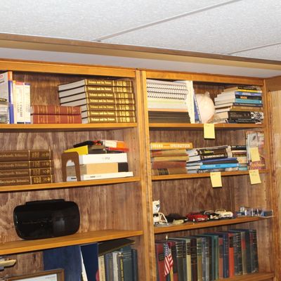 Sale Photo Thumbnail #120: Large wooden bookcase filled with vintage reference books, Encyclopædia Britannica volumes, Science and the Future yearbooks, small die-cast cars, and various media.