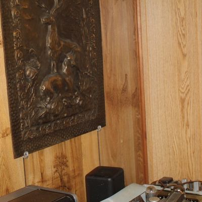 Sale Photo Thumbnail #111: Vintage embossed metal wall plaque depicting deer in a forest setting, mounted on wood-paneled walls.