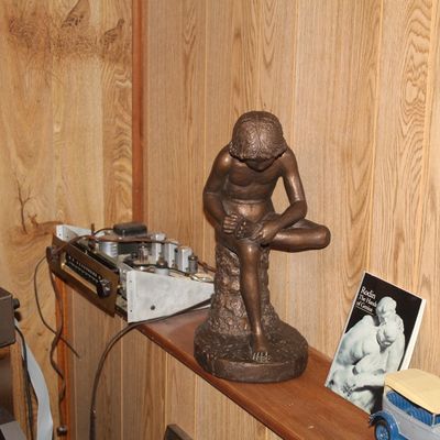 Sale Photo Thumbnail #127: Bronze-finish classical Spinario ('Boy with Thorn') statue displayed on a shelf alongside vintage electronics and art literature.