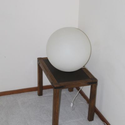Sale Photo Thumbnail #19: Vintage white frosted glass orb table lamp sitting atop a small rustic wooden side table with dark top insert.