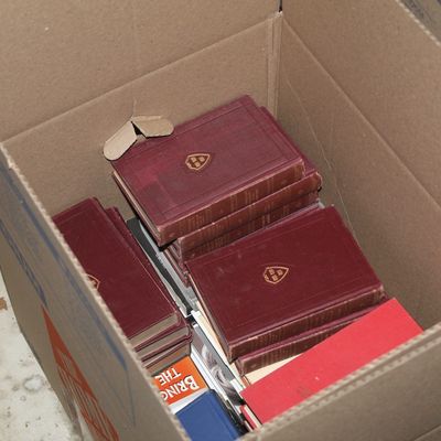 Sale Photo Thumbnail #143: Cardboard box containing a partial set of vintage red hardcover books featuring gold foil insignias on their covers, along with other miscellaneous books.