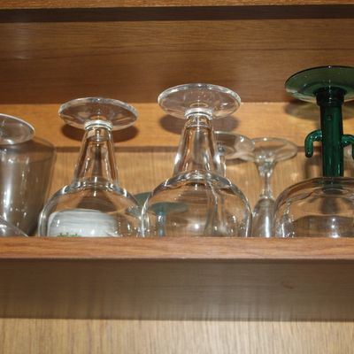 Sale Photo Thumbnail #64: Collection of upside-down glassware on a wooden shelf, including clear stems and a novel green cactus-stemmed margarita glass.