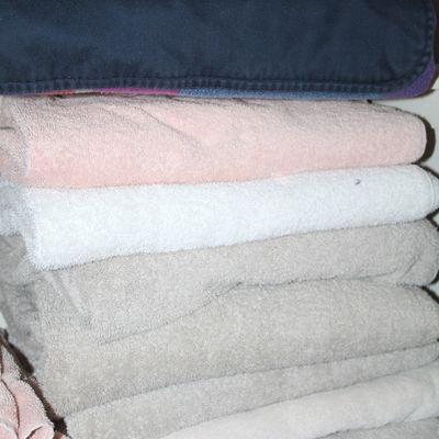 Sale Photo Thumbnail #11: Neatly folded stack of bath towels and blankets in pastel, grey, and navy colors.
