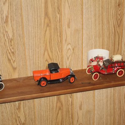 Sale Photo Thumbnail #115: Collection of vintage model cars, including an orange pickup truck and a red fire engine, displayed on a wooden shelf.