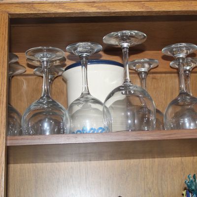 Sale Photo Thumbnail #57: Collection of stemware wine glasses stored upside down inside a oak wooden cabinet alongside a ceramic crock.