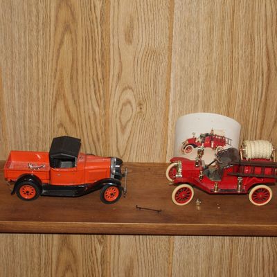 Sale Photo Thumbnail #119: Collection of vintage die-cast and metal toy vehicles, including an orange pickup truck and a red antique fire engine model with ladders.